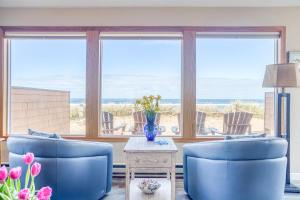 a living room with two blue chairs and a table with flowers at Breakers Beach House 9 - Meredith Lodging in Neskowin