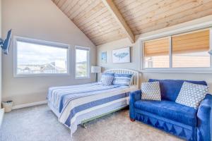a bedroom with a bed and a blue couch at Breakers Beach House 9 - Meredith Lodging in Neskowin