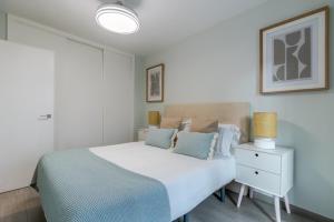 a bedroom with a white bed with blue pillows at UNIQUE HOMES LAS SETAS LA CAMPANA in Seville