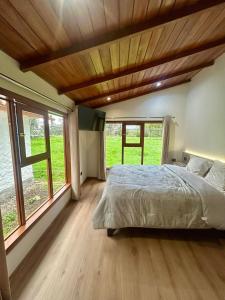 a bedroom with a large bed and windows at Casa del abuelo Lodge in Cajamarca