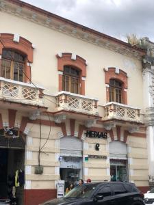 a building with balconies and a car parked in front of it at Hospedaje las Primicias 103 in Riobamba