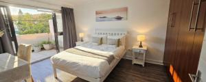 a bedroom with a white bed and a balcony at Sandstone - 2 x Bedroom Apartment! in Knysna