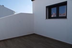 a white room with a window and a wooden floor at Refúgio de Ferrel in Ferrel