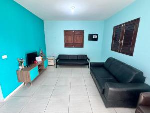 a living room with a black couch and blue walls at Beach House Sao Jose in São José da Coroa Grande