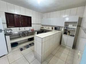 a large kitchen with white cabinets and a sink at Beach House Sao Jose in São José da Coroa Grande