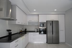 a kitchen with white cabinets and a stainless steel refrigerator at Refúgio de Ferrel in Ferrel