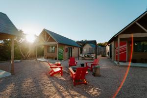 a group of red chairs and a picnic table in a yard at Lucky Arrow Retreat in Dripping Springs