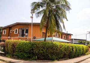 a house with a palm tree in front of a hedge at The 4 Kays Apartment - One Bedroom in Agege