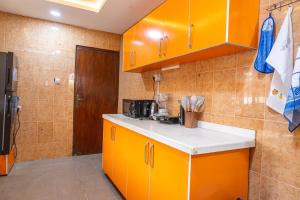 a kitchen with orange cabinets and a counter top at The 4 Kays Apartment - One Bedroom in Agege