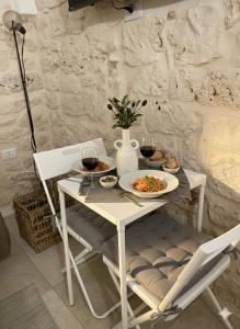 a table with two plates of food and two glasses of wine at Almurigini I Boutique House I Ceglie Messapica in Ceglie Messapica