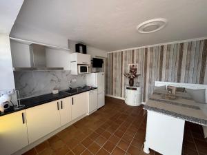 a kitchen with white cabinets and a tile floor at Torkes in Foz