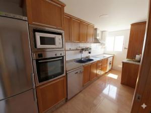 a kitchen with wooden cabinets and stainless steel appliances at Apartamento en primera línea de la playa a 15 minutos de la Ciudad de Valencia in Valencia