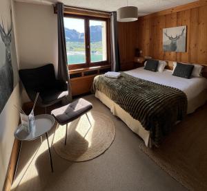 a bedroom with a bed and a chair and a window at Chalet de Roselend in Beaufort