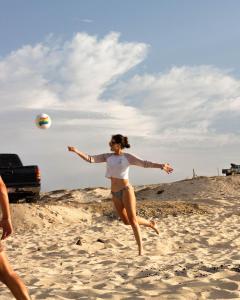 a woman in a bikini playing with a volleyball on the beach at Amina Wind Resort by Tasman in Salinas