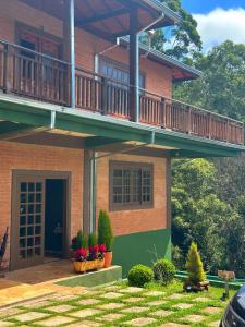 a house with a balcony and flowers in a yard at Pousada All Green - Monte Verde in Monte Verde