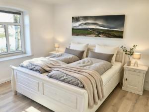 a large white bed in a room with two lamps at Hof Steinhütten Boutique Apartments in Westerhever