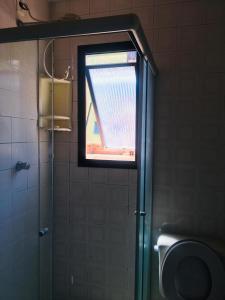 a window in a bathroom with a shower and a toilet at Edifício Nautilus in Guarujá +19 photos