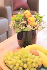 a vase filled with flowers and a plate of grapes at BB Blick Hotel und Café in Bad Bellingen
