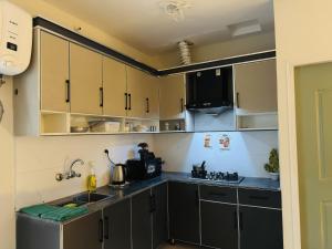 a kitchen with gray cabinets and a sink at Stay Homie - 1BHK, Near ISB Airport, Self Check-In, Secure in Islamabad