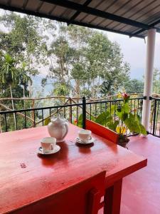 a red table with two cups and a tea pot on it at Mount View Plaza - Ella Cottage with Mountain &Valley View in Ella