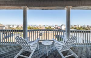 three chairs and a table on a deck with a view at Funtiki - S Nags Head MP 17.5, Semi-Oceanfront, 150 Yds to Beach, Pool, Hot Tub, Pool Table, Pets OK in Whalebone