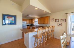 a kitchen with wooden cabinets and a island with bar stools at Funtiki - S Nags Head MP 17.5, Semi-Oceanfront, 150 Yds to Beach, Pool, Hot Tub, Pool Table, Pets OK in Whalebone