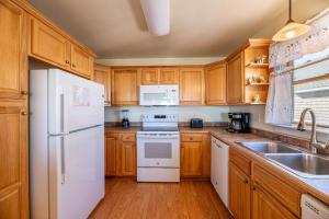 a kitchen with wooden cabinets and white appliances at Funtiki - S Nags Head MP 17.5, Semi-Oceanfront, 150 Yds to Beach, Pool, Hot Tub, Pool Table, Pets OK in Whalebone