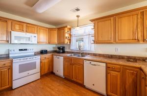 a kitchen with wooden cabinets and white appliances at Funtiki - S Nags Head MP 17.5, Semi-Oceanfront, 150 Yds to Beach, Pool, Hot Tub, Pool Table, Pets OK in Whalebone +59 photos