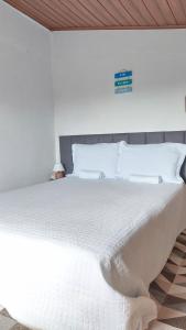 a bedroom with a large white bed with white pillows at Chalé Almar - Praia do Sagi in Baía Formosa
