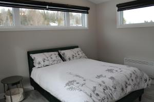 a bedroom with a bed with white sheets and windows at La Casa TiMoris in Wentworth-Nord
