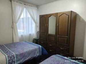 a bedroom with a large wooden cabinet and a bed at Casa Amoblada para Empresas in Los Ángeles