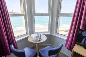 a table and chairs in a room with windows at The Beresford Hotel in Newquay +1 photo