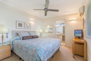 a bedroom with a bed and a flat screen tv at Bali Hai Apartments Noosa in Noosa Heads