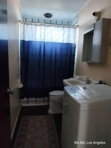 a bathroom with a blue shower curtain and a sink at Casa Amoblada para Empresas in Los Ángeles