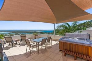 a patio with a hot tub and tables and chairs at Bali Hai Apartments Noosa in Noosa Heads