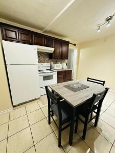 a kitchen with a table and a white refrigerator at Cozy Private Apartment with 2 Queen size Beds in Moncton
