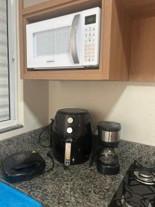 a kitchen counter with a coffee maker and a microwave at Studio J&C in Primavera do Leste