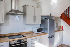 a kitchen with white cabinets and a microwave at Waders in Salcombe