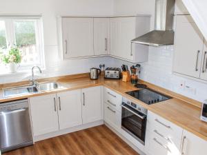 a kitchen with white cabinets and a sink at Waders in Salcombe +27 photos