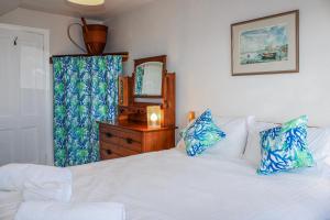 a bedroom with a white bed with blue pillows and a mirror at Waders in Salcombe