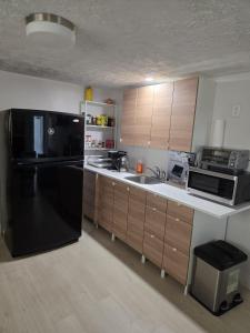 a kitchen with a black refrigerator and wooden cabinets at Garden City-Private 1BR Full Apt in Halifax