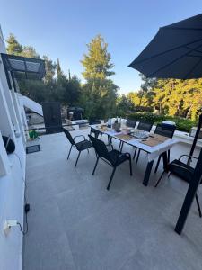 a table with chairs and an umbrella on a patio at Cassa Luca in Glarokavmos in Paliouri