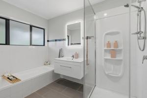 a white bathroom with a shower and a sink at Clay Cottage in Waimauku