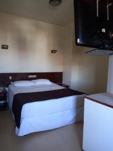 a bedroom with a bed and a flat screen tv at Cheverny Apart Hotel in Belo Horizonte