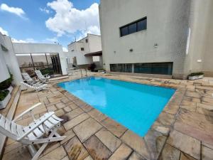 a swimming pool with chairs and a building at Flat Próx. Campo de Marte, Anhembi e Espaço Unimed in São Paulo