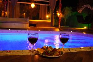two glasses of wine and a plate of food next to a pool at ON2 Bungalov Villas in Dosemealti