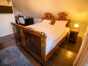 a bedroom with a large wooden bed with white sheets at Casa Kresován in Sarmizegetusa