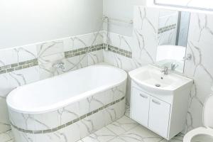 a white bathroom with a sink and a toilet at Blueroof BYO in Bulawayo
