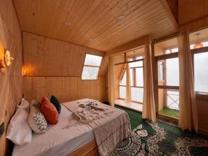 a bedroom with a bed in a room with windows at The nature view A shaped tree cottage in Banjār