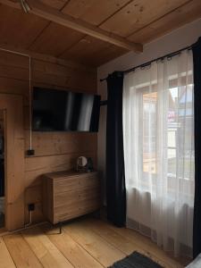 a bedroom with a tv and a window with a curtain at Villa Podhalańska 1959 in Biały Dunajec